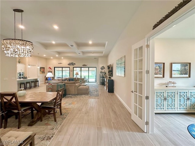 dining room with a notable chandelier, light hardwood / wood-style floors, french doors, and a tray ceiling