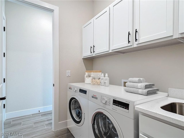 washroom with cabinets, light hardwood / wood-style floors, and washer and dryer