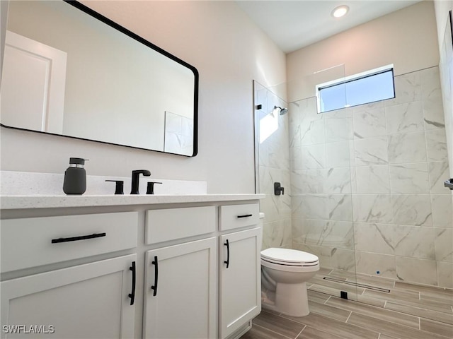 bathroom featuring vanity, tiled shower, and toilet