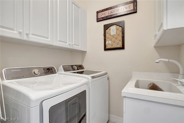 clothes washing area with separate washer and dryer, sink, and cabinets