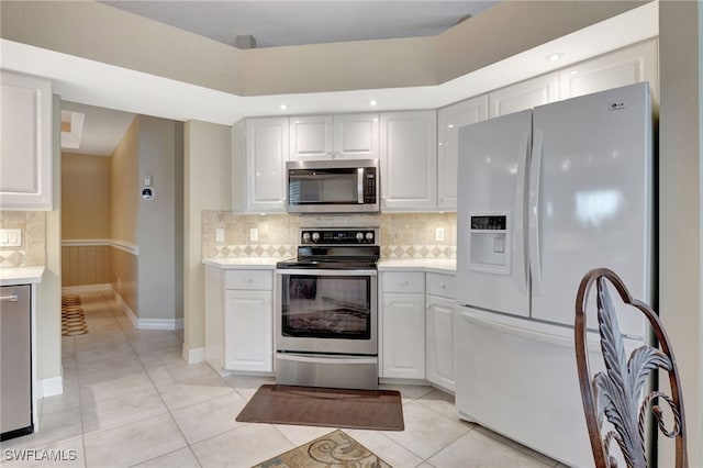 kitchen featuring light tile patterned floors, backsplash, stainless steel appliances, and white cabinetry