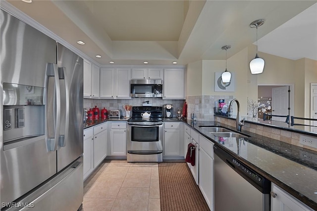 kitchen featuring white cabinets, sink, hanging light fixtures, dark stone countertops, and stainless steel appliances