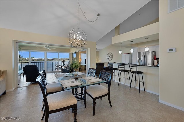 dining space with ceiling fan with notable chandelier, light tile patterned flooring, and high vaulted ceiling