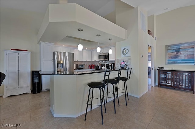 kitchen with white cabinets, tasteful backsplash, decorative light fixtures, kitchen peninsula, and stainless steel appliances