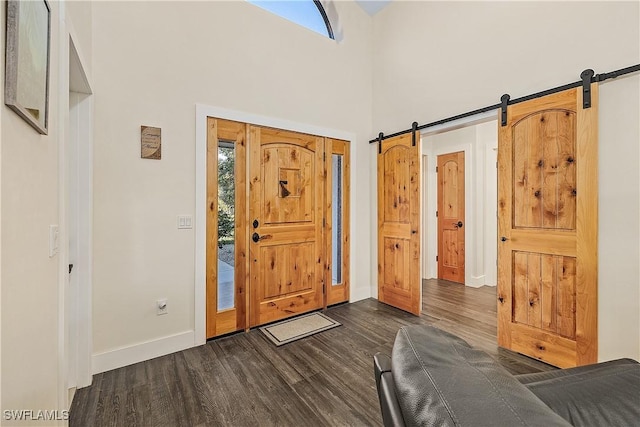 entrance foyer featuring a barn door, dark wood-type flooring, and a high ceiling