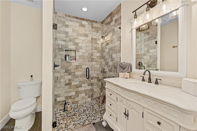 bathroom with hardwood / wood-style floors, vanity, toilet, and a shower with door