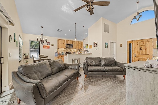 living room with light hardwood / wood-style flooring, high vaulted ceiling, and ceiling fan with notable chandelier