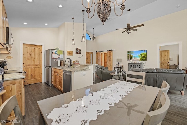 dining room featuring a barn door, sink, high vaulted ceiling, and dark wood-type flooring