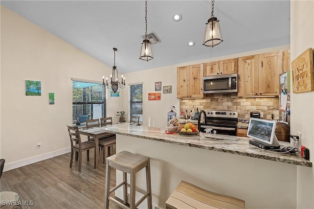 kitchen with light stone countertops, light brown cabinets, stainless steel appliances, dark hardwood / wood-style flooring, and decorative light fixtures