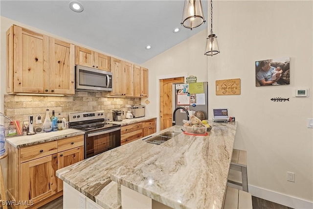 kitchen with a kitchen breakfast bar, sink, hanging light fixtures, light stone countertops, and appliances with stainless steel finishes