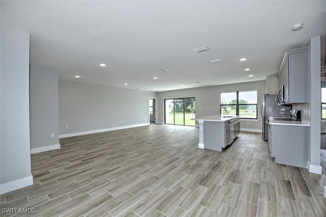 kitchen featuring gray cabinetry, sink, a center island, stainless steel appliances, and light wood-type flooring