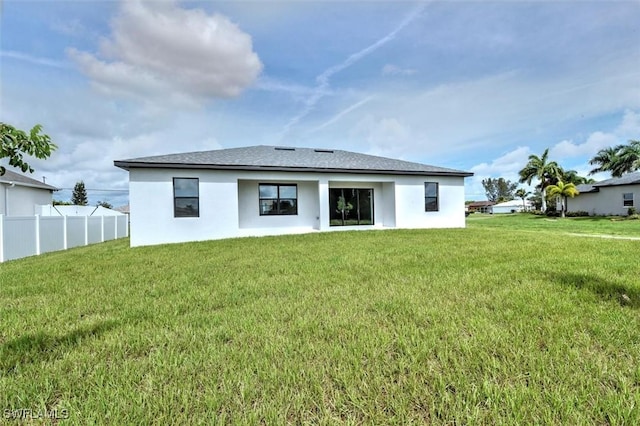 rear view of property featuring a lawn