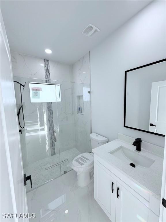 bathroom with a shower with door, vanity, and toilet