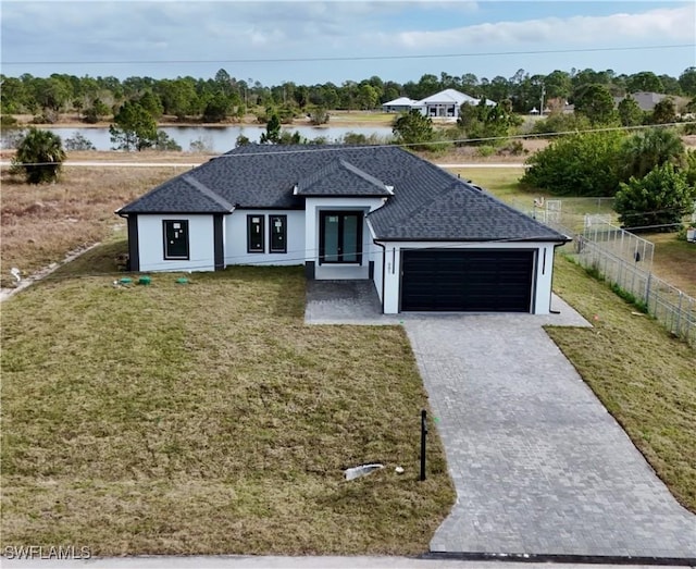 view of front facade with a front lawn, a water view, and a garage