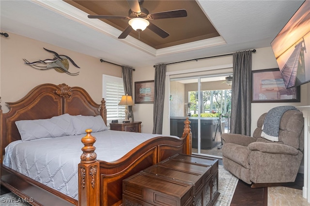 bedroom with hardwood / wood-style floors, a tray ceiling, and ceiling fan