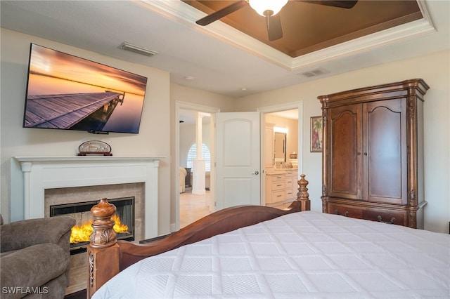 bedroom featuring a raised ceiling, connected bathroom, and ceiling fan