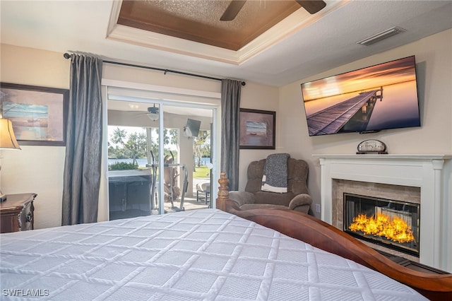 bedroom with a raised ceiling, access to exterior, ceiling fan, and a textured ceiling