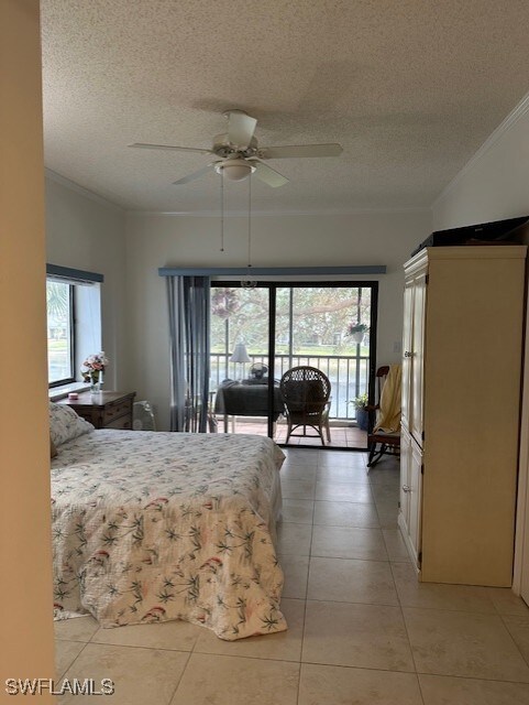 bedroom featuring ceiling fan, light tile patterned floors, a textured ceiling, and ornamental molding