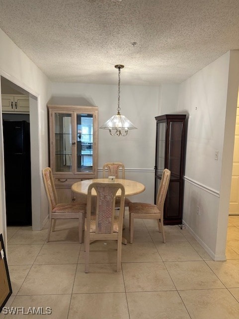 tiled dining area with a textured ceiling and an inviting chandelier