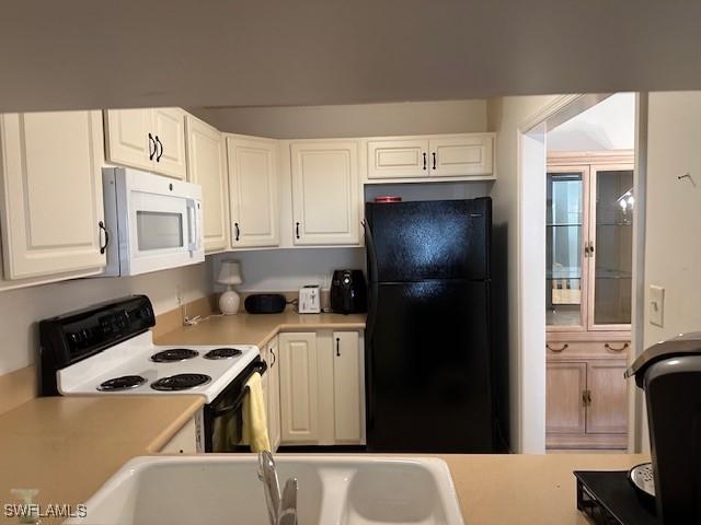 kitchen with sink, white cabinets, and white appliances