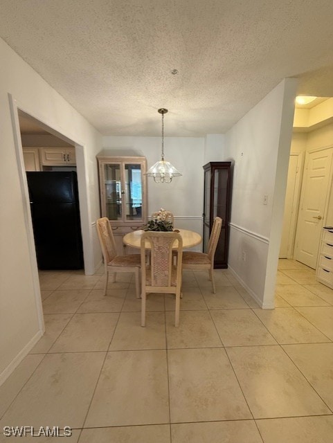 dining area with a chandelier, light tile patterned floors, and a textured ceiling