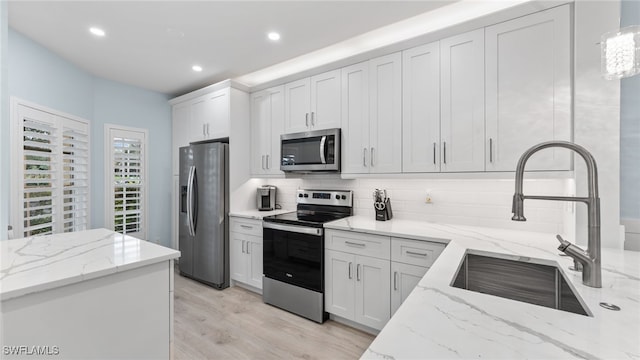 kitchen with white cabinets, appliances with stainless steel finishes, and light stone counters