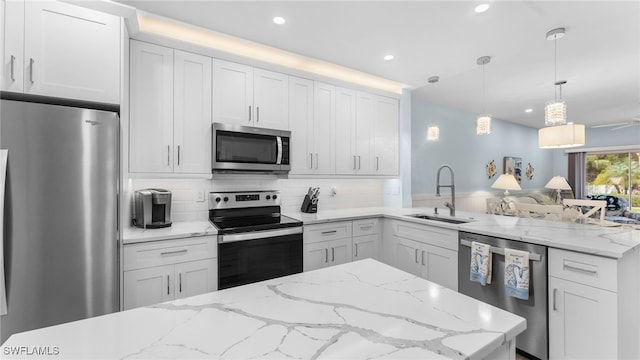 kitchen featuring white cabinetry, sink, decorative light fixtures, and appliances with stainless steel finishes