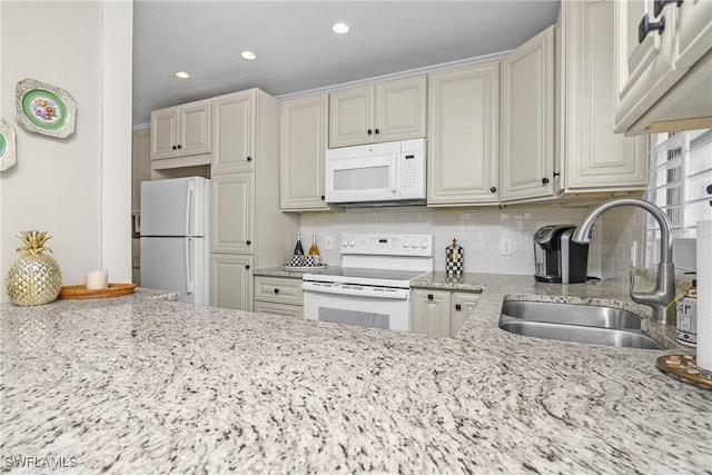 kitchen with light stone counters, white appliances, sink, and tasteful backsplash