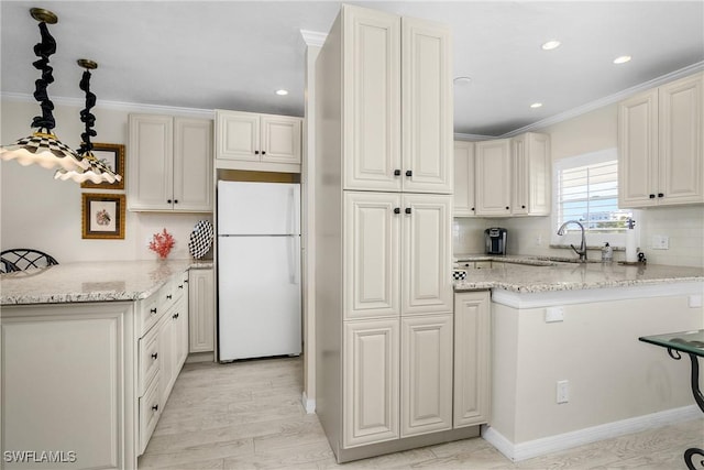 kitchen featuring kitchen peninsula, white fridge, white cabinetry, and crown molding