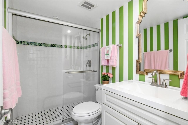 bathroom featuring vanity, a shower with shower door, and toilet