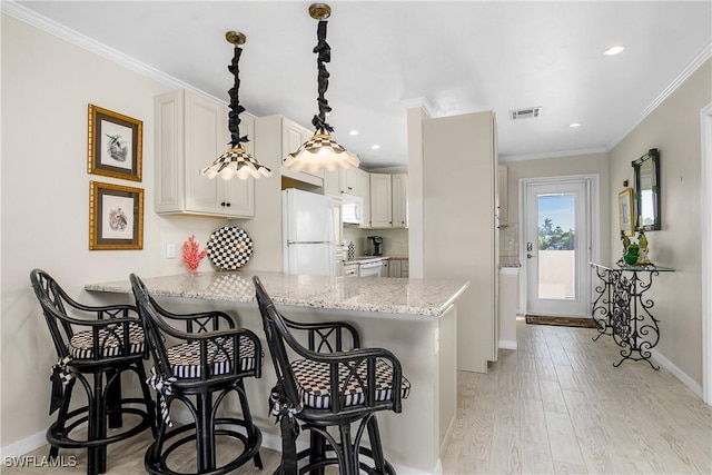 kitchen with kitchen peninsula, decorative light fixtures, white appliances, a breakfast bar, and ornamental molding