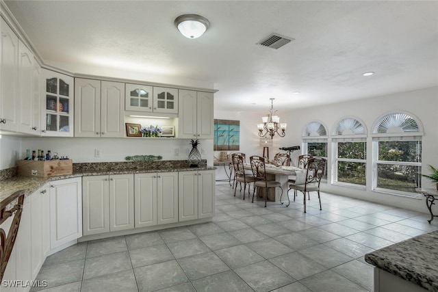 kitchen featuring white cabinets, hanging light fixtures, dark stone counters, and light tile patterned flooring