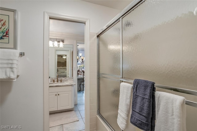 bathroom with tile patterned flooring, vanity, and bath / shower combo with glass door