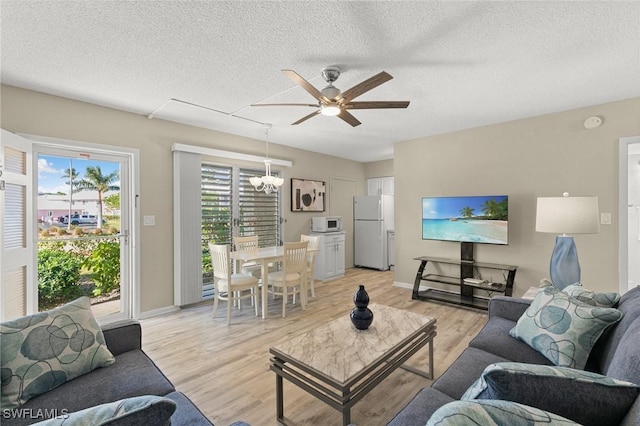 living room featuring ceiling fan, light hardwood / wood-style flooring, and a textured ceiling