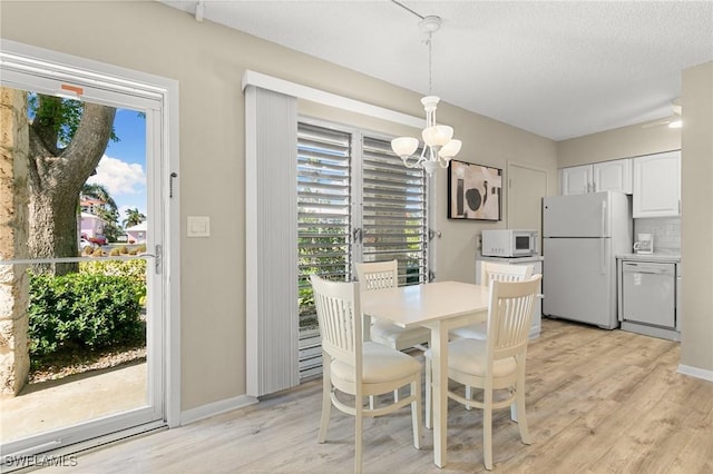 dining area featuring a textured ceiling, light wood-type flooring, and a healthy amount of sunlight