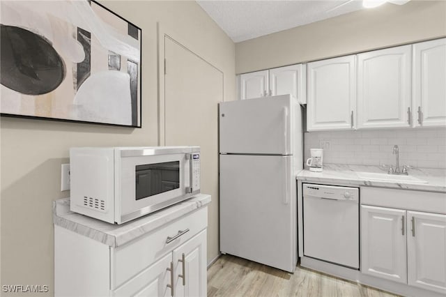 kitchen featuring white appliances, white cabinets, sink, light wood-type flooring, and a textured ceiling