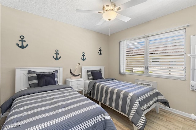 bedroom with ceiling fan, light hardwood / wood-style floors, and a textured ceiling