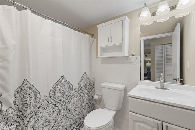 bathroom with vanity, toilet, and tile walls