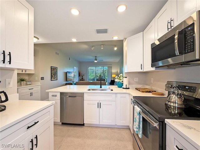 kitchen with kitchen peninsula, sink, white cabinets, and appliances with stainless steel finishes