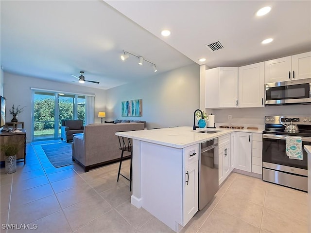 kitchen with ceiling fan, sink, kitchen peninsula, white cabinets, and appliances with stainless steel finishes