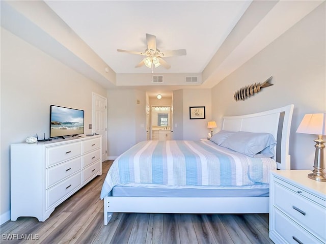 bedroom with a tray ceiling, ceiling fan, and wood-type flooring