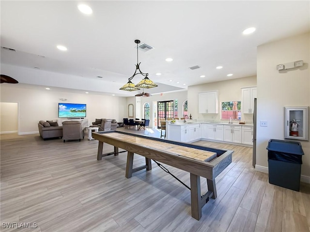 rec room with sink and light wood-type flooring