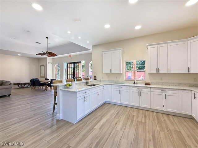 kitchen with ceiling fan, white cabinetry, kitchen peninsula, and sink