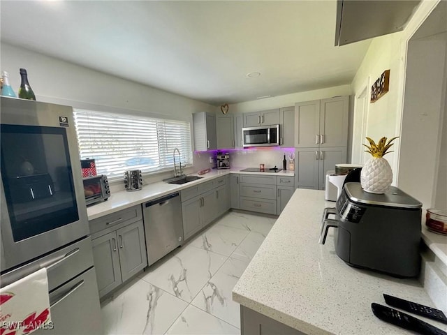 kitchen with gray cabinetry, appliances with stainless steel finishes, decorative backsplash, and sink