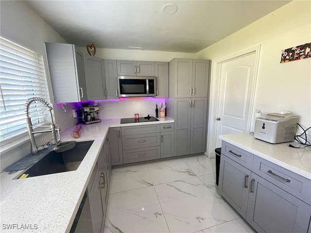 kitchen featuring black electric stovetop, sink, plenty of natural light, light stone counters, and gray cabinetry