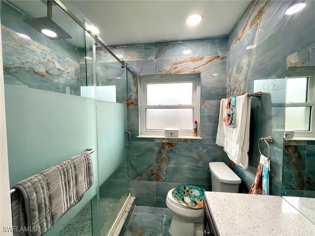 bathroom with toilet, vanity, tile walls, and a shower with door