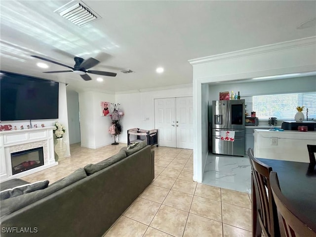 tiled living room with ceiling fan and crown molding