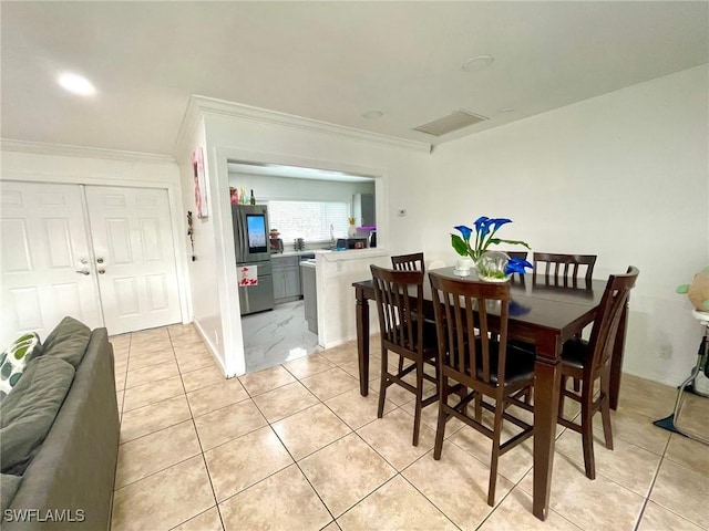 dining room with light tile patterned floors and ornamental molding