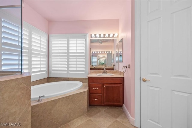 bathroom featuring tiled tub, a wealth of natural light, tile patterned flooring, and vanity