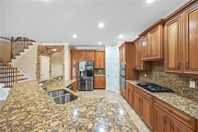 kitchen featuring appliances with stainless steel finishes, tasteful backsplash, ornamental molding, dark stone counters, and sink